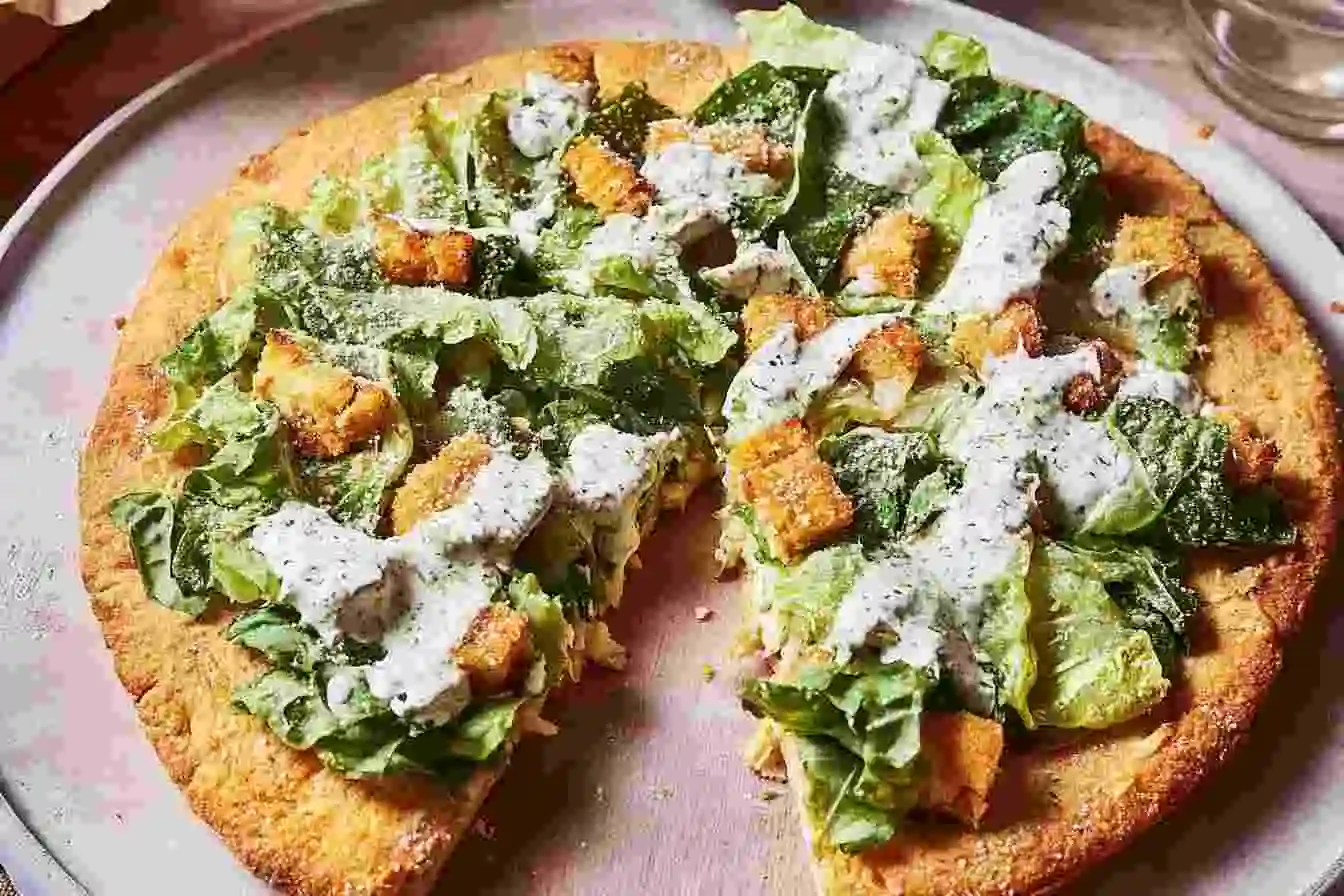 Healthy chicken crust Caesar salad pizza topped with romaine lettuce and Parmesan cheese