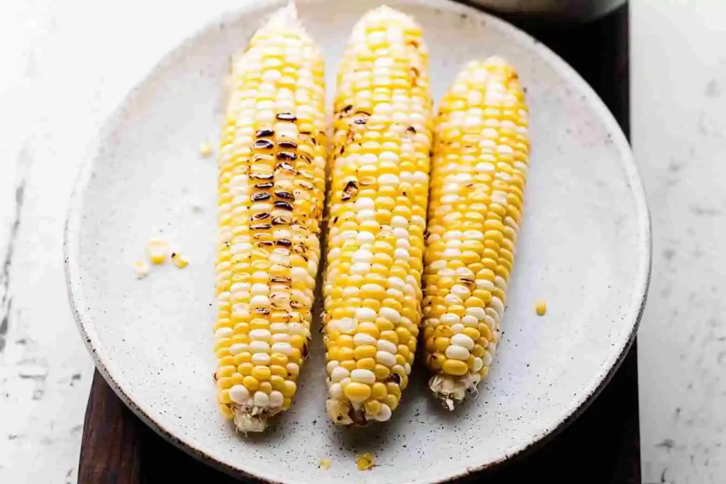 Grilled street corn (elote) topped with mayo, chili powder, cotija cheese, and a squeeze of lime