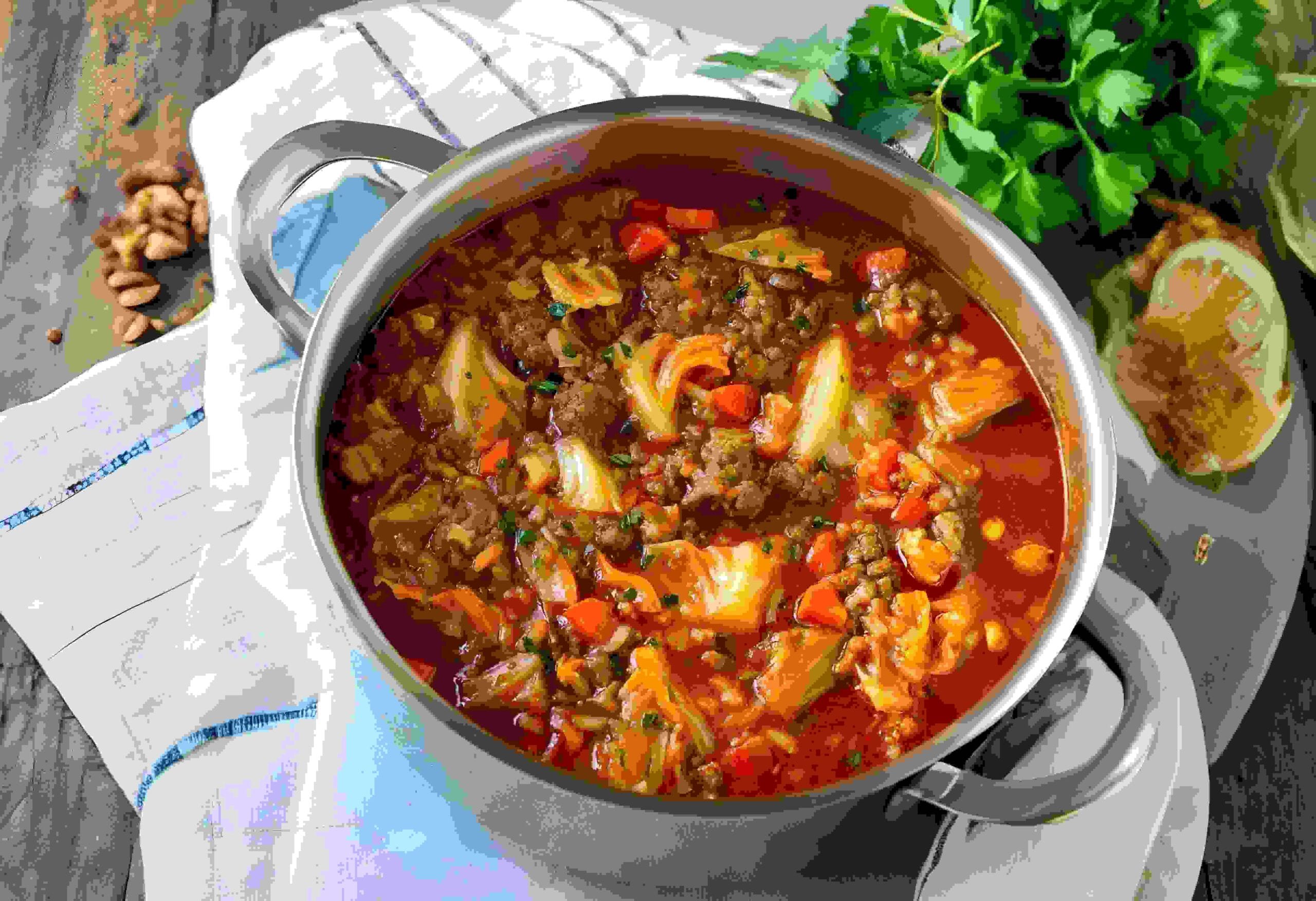 A bowl of homemade cabbage soup with ground beef, carrots, and cabbage in a rich broth.