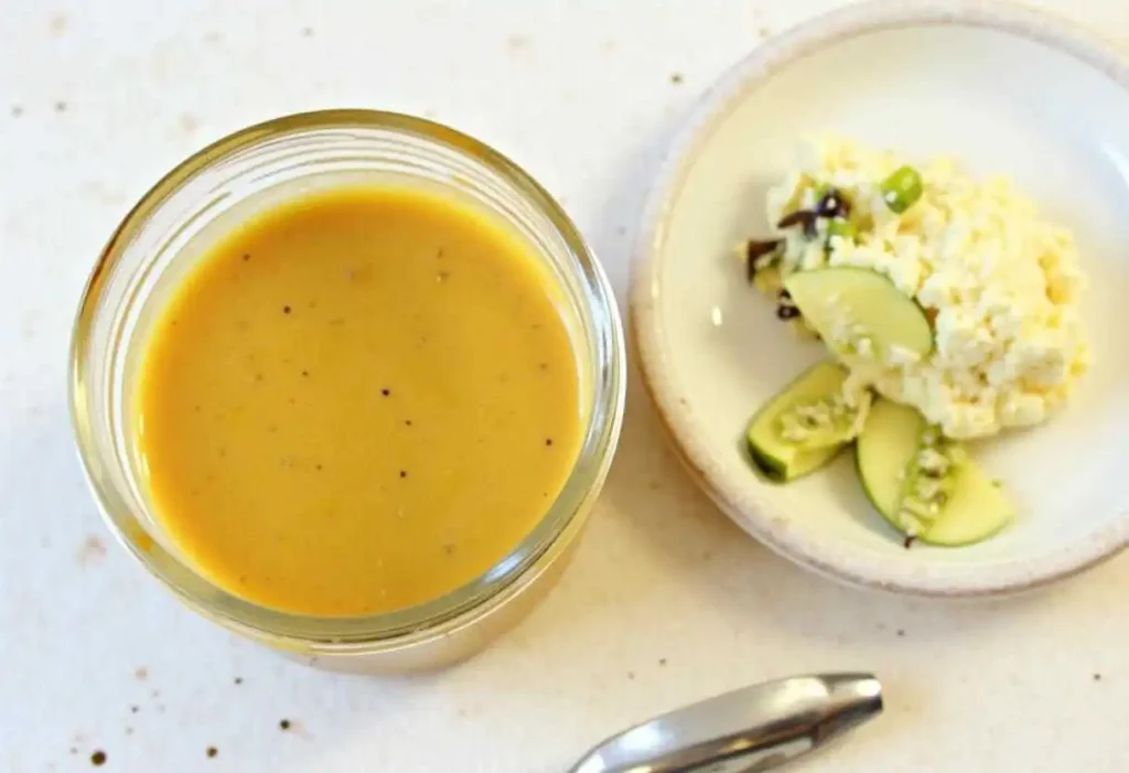 Step-by-step process of making New Orleans soaked salad dressing, showing a bowl with whisked olive oil, vinegar, Dijon mustard, and spices being mixed together.