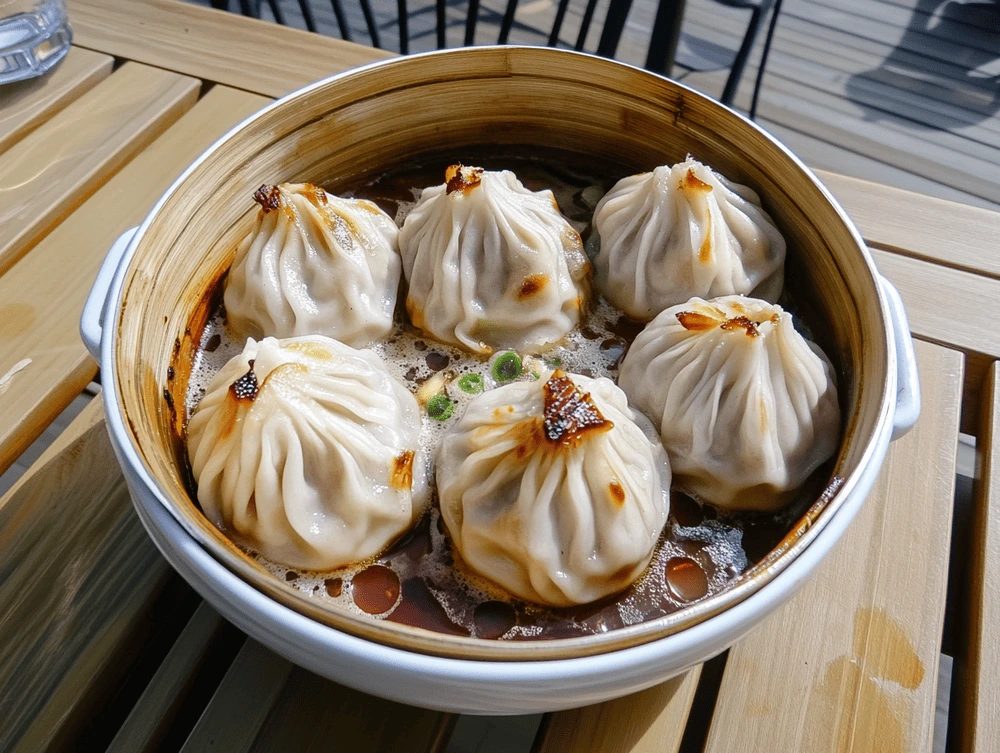 A close-up of freshly steamed vegan soup dumplings in a bamboo steamer, with dipping sauce on the side.